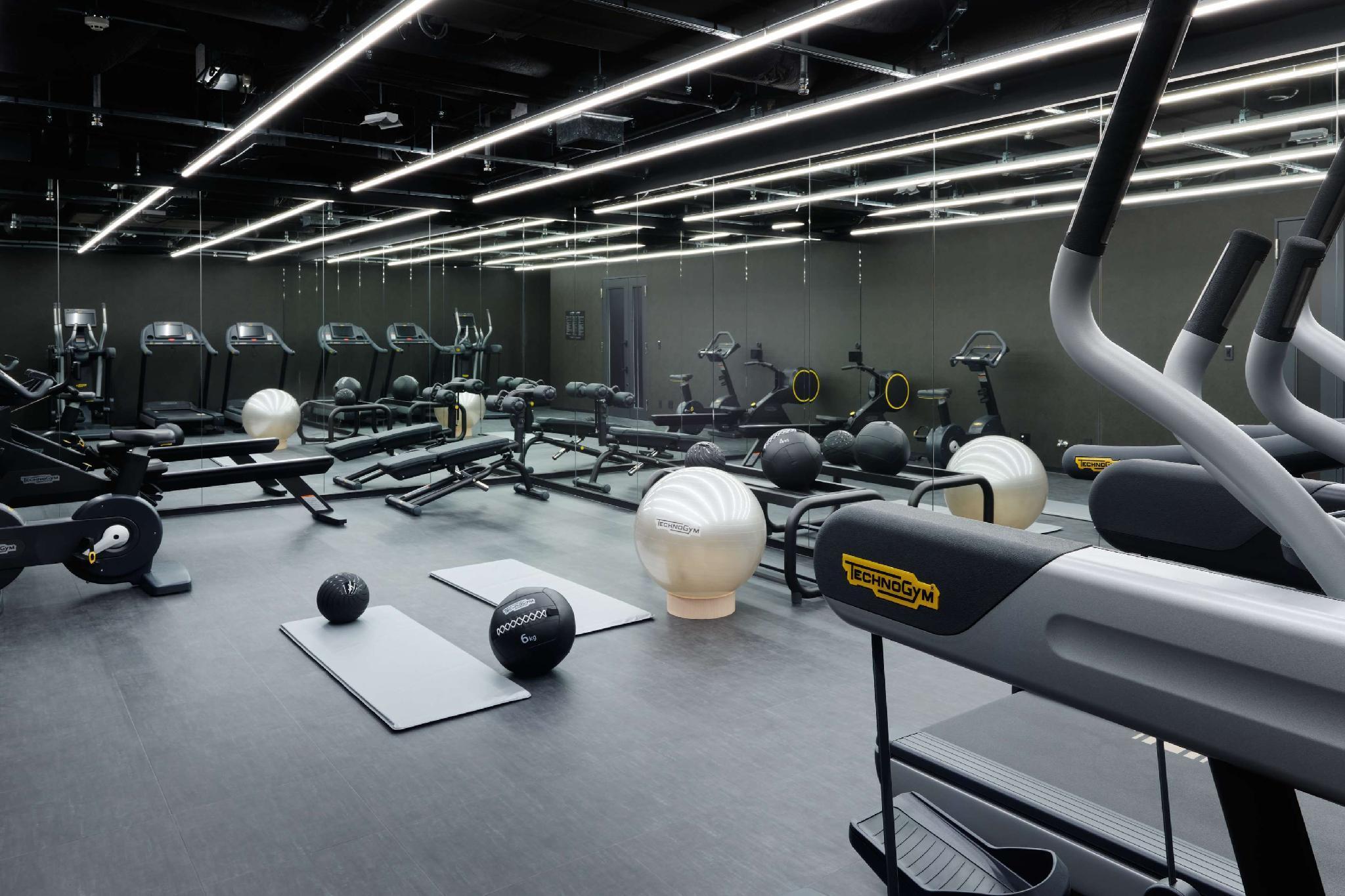 Mitsui Garden Hotel Roppongi Tokyo Premier Экстерьер фото The photo shows a modern gym interior. The space features various exercise equipment, including cardio machines like treadmills and elliptical trainers, weight machines, and free weights. There are also exercise mats and fitness balls scattered throu